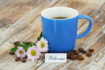 Fototapeta na wymiar Welcome card with mug of coffee and pink daisies on rustic wooden surface 