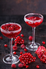 Red alcoholic cocktail with raspberry and pomegranate, in a glass glass on a black background. selective focus.