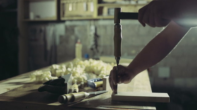 joiner cuts a groove in the wooden workpiece with a chisel