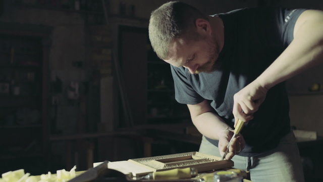 joiner makes notches on the wooden workpiece with curved chisel