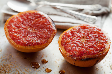 Vintage image of broiled grapefruit with brown sugar and cinnamon on metal surface, healthy dessert is good for breakfast or snacks