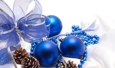 blue Christmas balls with  a beautiful bow on white satin fabric