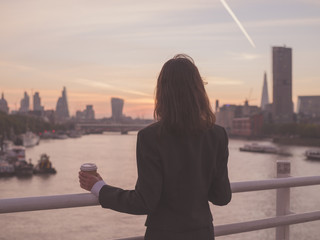 Fototapeta na wymiar Businesswoman with cup admiring sunrise in London