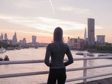 Young woman wearing hoodie on bridge in London at sunrise