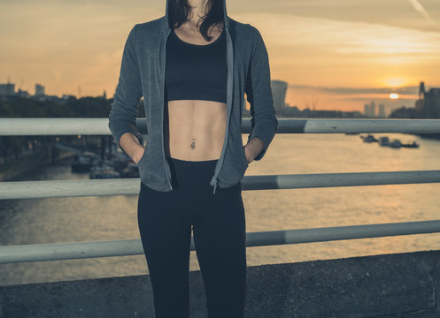 Athletic young woman on bridge at sunrise