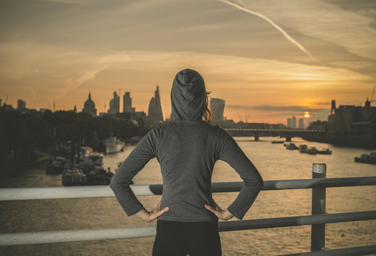 Young woman wearing hoodie on bridge in London at sunrise
