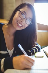 Smiling student writing on notebook