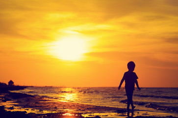 Fototapeta na wymiar little boy walking on sunset beach