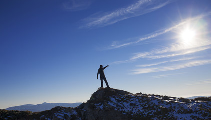 Silhouette of a girl on top of a mountain.