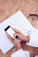 Doctor using smartphone on wooden desk 