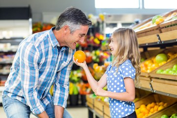 Cute girl holding an orange to her father