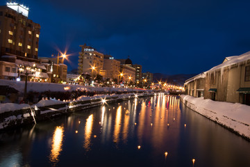 Naklejka premium Light on canal, snow is stopping in Otaru Snow Light Path Festival. snow cover the road 