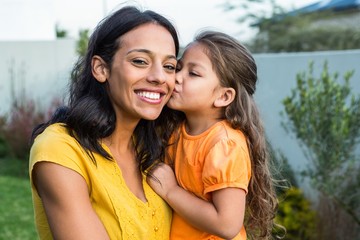 Cute daughter kissing her mothers cheek