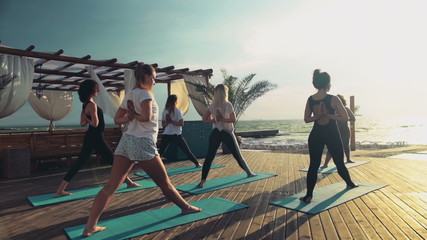 group of women practicing yoga on the beach slow motion