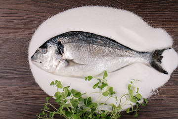 Fresh Dorado fish on salt  on  wooden background. Healthy food concept