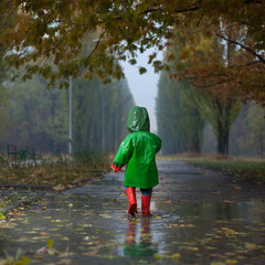 Baby walking in autumn rainy park