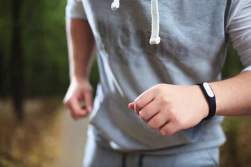 Photo sur Plexiglas Jogging young man using fitness bracelet during morning run