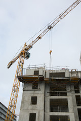 Fototapeta na wymiar A new building is being constructed with use of tower crane
