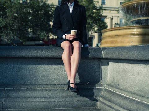 Young businesswoman with coffee by fountain