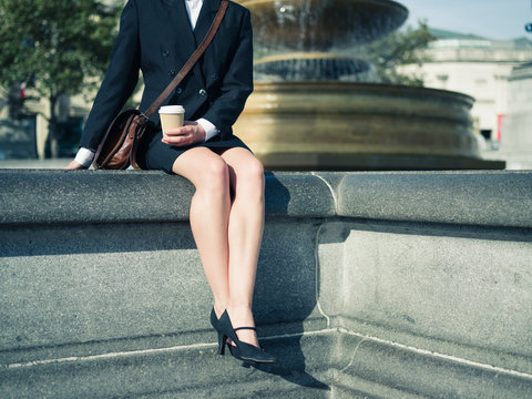 Young businesswoman with coffee by fountain