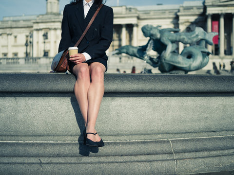 Young businesswoman sitting by fountain in city