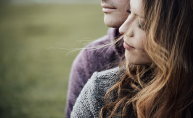 Young loving couple sitting on the grass - obrazy, fototapety, plakaty