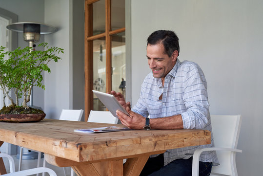 Smiling man using digital tablet surfing internet sitting outsid