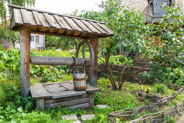 Wooden fence and an old well in the garden of the rural house