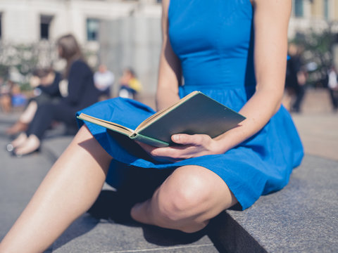 Young woman reading in the city