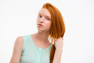 Young woman making hairdo with her long red hair
