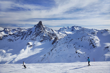 Fototapeta na wymiar Skiers on a downhill run with mountain backdrop, Three Valleys ski resort, France.