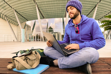 Businessman with pc sitting outdoor - Attractive guy smiling using laptop online - Trendy hipster...
