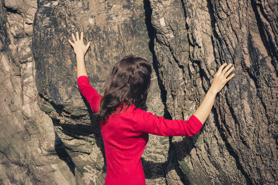 Woman in red dress touching rock wall
