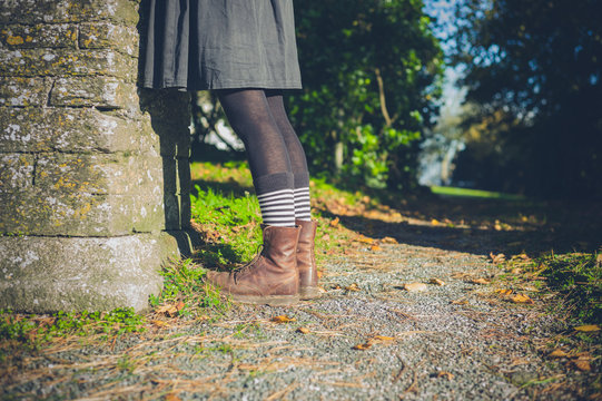 Legs of young woman in the countryside by wall