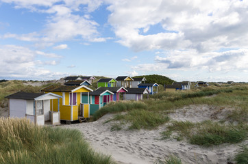 Bunte schwedische Strandhütten hinter einer Düne.