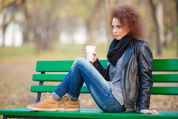Woman sitting on the bench and holding cup with coffee
