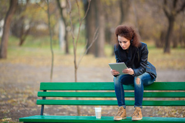 Fototapeta premium Woman sitting on the bench and using tablet computer