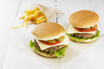 Burgers and french fries on a white wooden background
