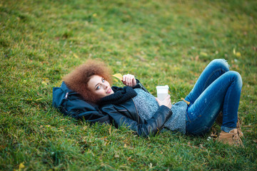 Woman lying on green grass with cup of coffee