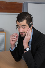 Happy Businessman in the office on the phone, headset,  looking camera