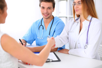 Male doctor and female patient shaking hands. Partnership, trust and medical ethics concept