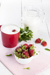 Bowl with strawberry, glass and jug with milk, mint on white woo