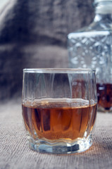 Carafe and glass of whisky, whiskey bourbon on a burlap, sacks background