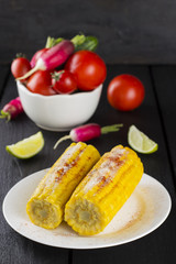 Corncob, tomato, radish, cherry tomatoes in white bowl and lime