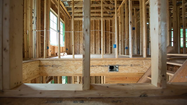 Second Floor Residential New Home Construction. camera moves right on a new under construction home. shot from upstairs room. shows framing and bare beams for roof. architecture and construction
