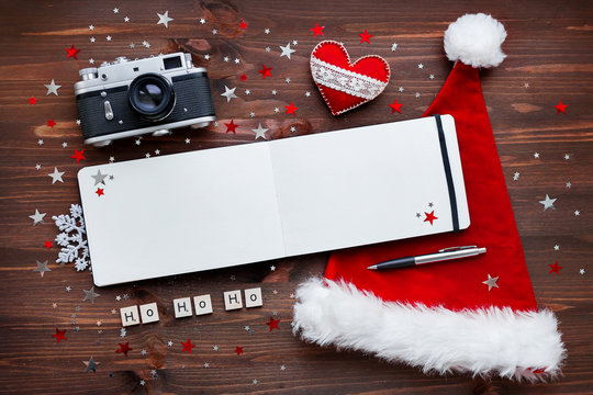 Christmas and New Year background with old camera, Santa's hat and notepad with words Ho-ho-ho.
