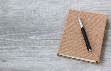 A diary book and a pen on the wood background