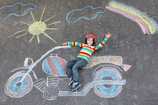 Little kid boy in helmet with motorcycle chalks picture