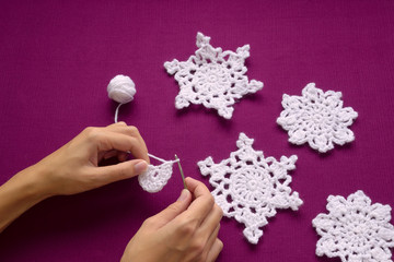 Woman knits Christmas decoration – snowflakes