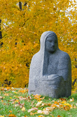 Religious stone figure of a woman against autumnal trees